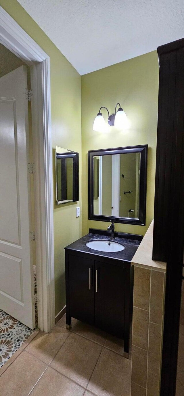 bathroom with a textured ceiling, tile patterned floors, and vanity