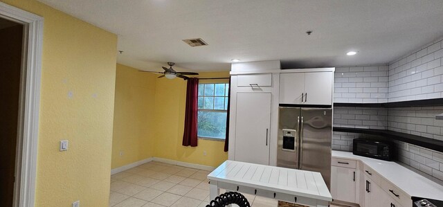 kitchen with tasteful backsplash, ceiling fan, white cabinetry, stainless steel fridge with ice dispenser, and light tile patterned floors