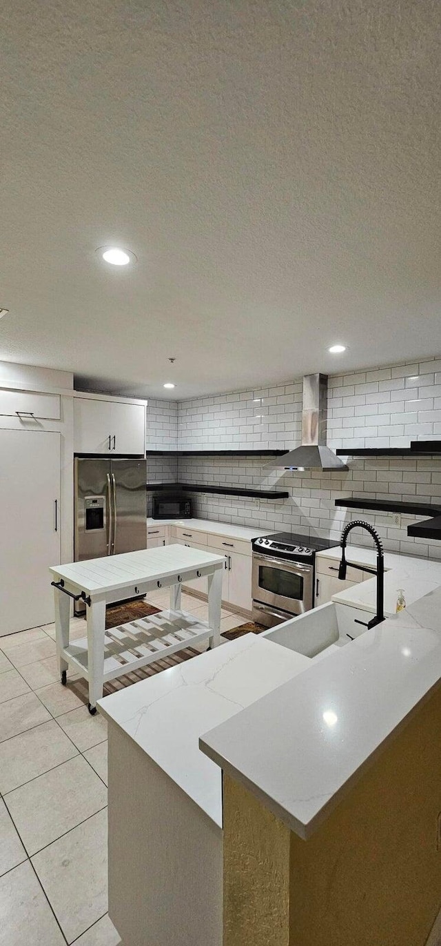 kitchen featuring appliances with stainless steel finishes, wall chimney exhaust hood, white cabinetry, and a center island