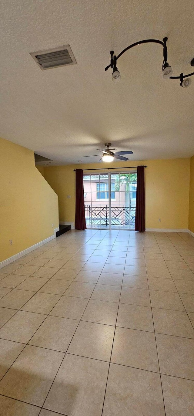 tiled empty room with ceiling fan and a textured ceiling