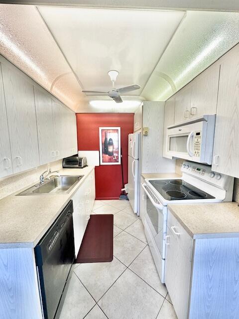 kitchen with sink, white appliances, light tile patterned floors, and ceiling fan