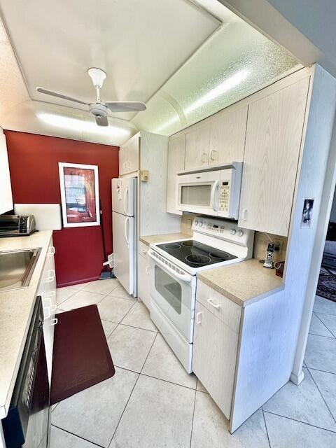 kitchen with sink, light tile patterned floors, ceiling fan, and white appliances