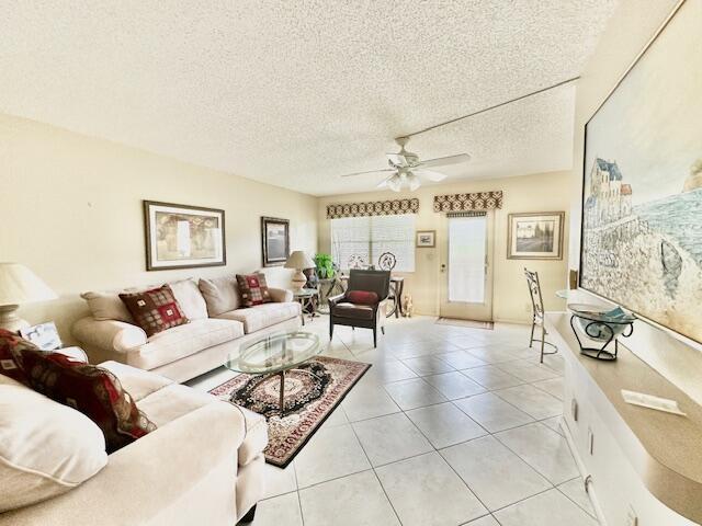 tiled living room featuring ceiling fan and a textured ceiling