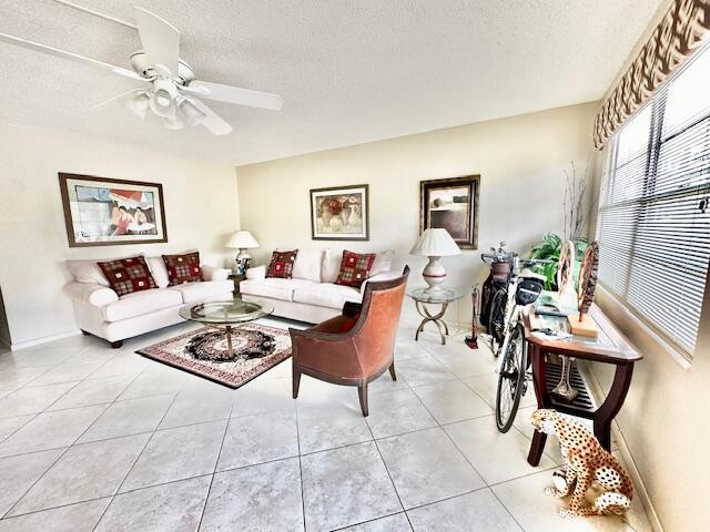 tiled living room featuring ceiling fan and a textured ceiling