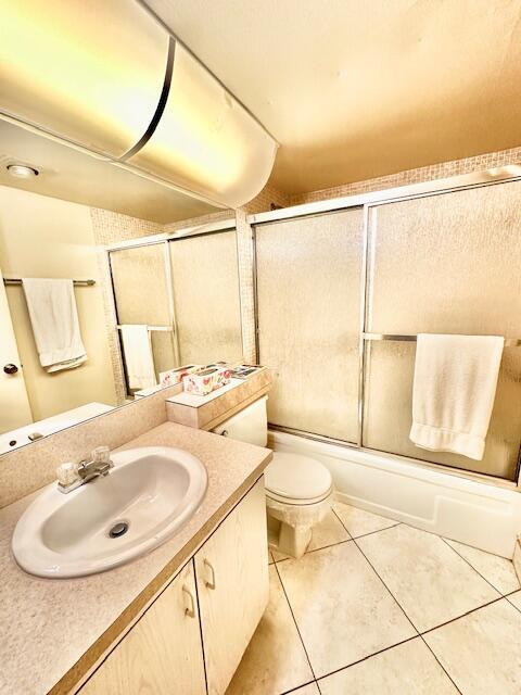 full bathroom with vanity, toilet, tile patterned flooring, and combined bath / shower with glass door