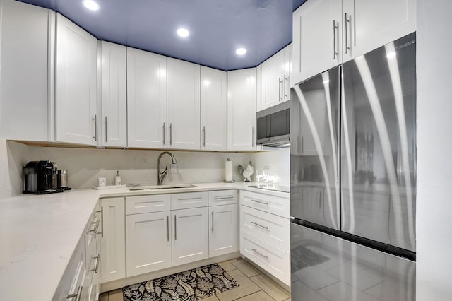 kitchen with sink, white cabinetry, stainless steel appliances, and light tile patterned floors