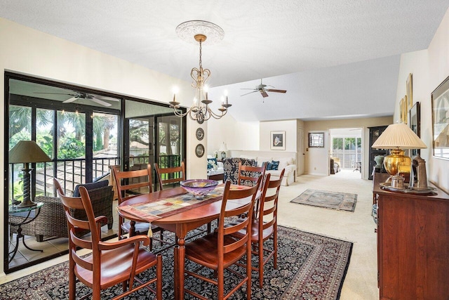 dining area with lofted ceiling, ceiling fan with notable chandelier, light colored carpet, and a textured ceiling