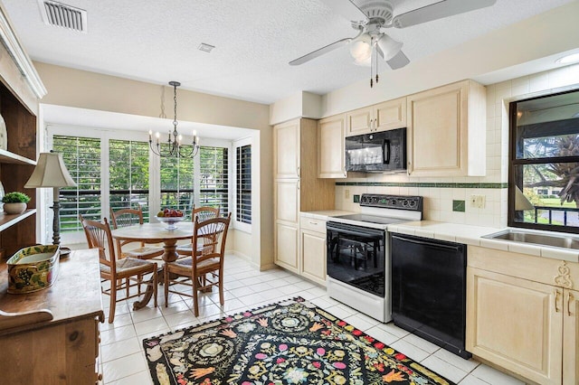 kitchen with decorative light fixtures, ceiling fan with notable chandelier, black appliances, tile counters, and tasteful backsplash