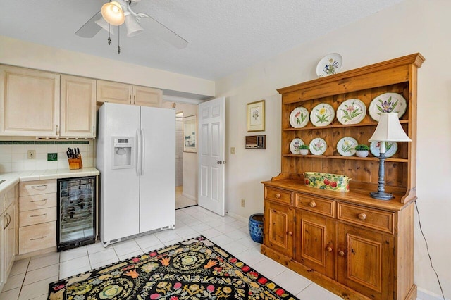 kitchen featuring a textured ceiling, wine cooler, tasteful backsplash, white fridge with ice dispenser, and ceiling fan