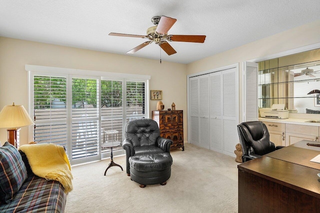 carpeted home office featuring a textured ceiling and ceiling fan