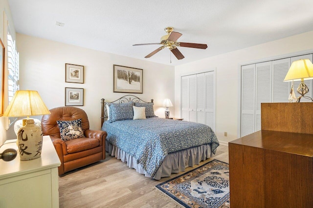 bedroom featuring ceiling fan, multiple closets, and light hardwood / wood-style flooring