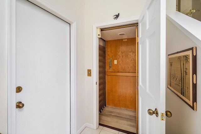 hallway featuring elevator and light tile patterned flooring