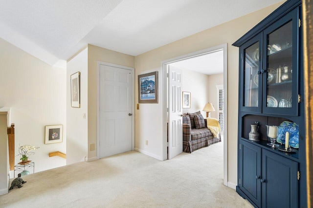 hallway with light carpet and a textured ceiling