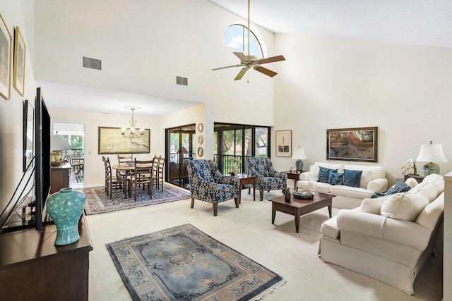 carpeted living room featuring plenty of natural light, ceiling fan with notable chandelier, and high vaulted ceiling