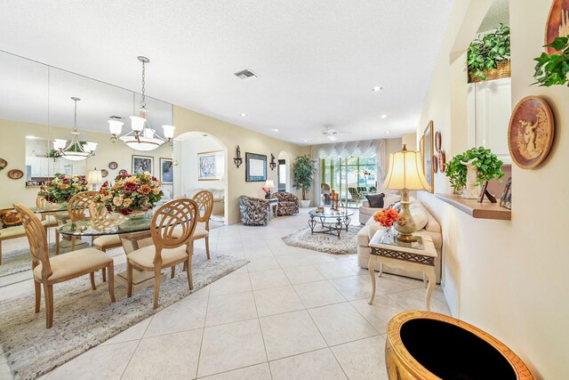 dining area with light tile patterned flooring and ceiling fan with notable chandelier