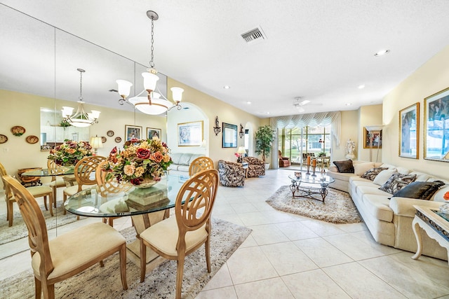 tiled dining room with ceiling fan with notable chandelier