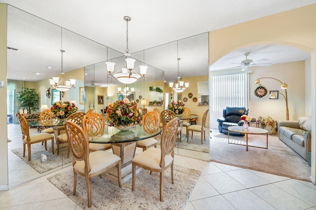 tiled dining room with ceiling fan with notable chandelier