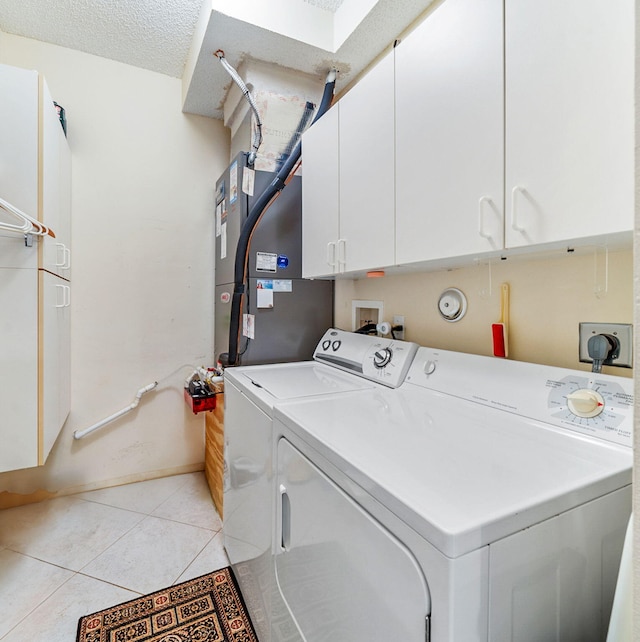 washroom featuring cabinets, washer and clothes dryer, light tile patterned floors, and a textured ceiling