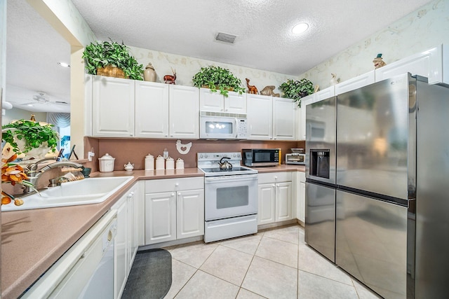 kitchen featuring white cabinets, sink, appliances with stainless steel finishes, a textured ceiling, and light tile patterned floors