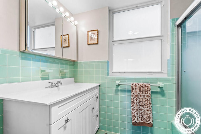 bathroom featuring vanity, a shower with shower door, and tile walls