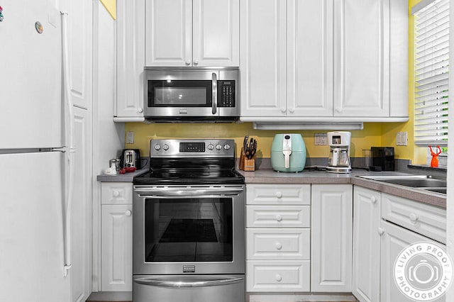 kitchen with appliances with stainless steel finishes, white cabinetry, and sink