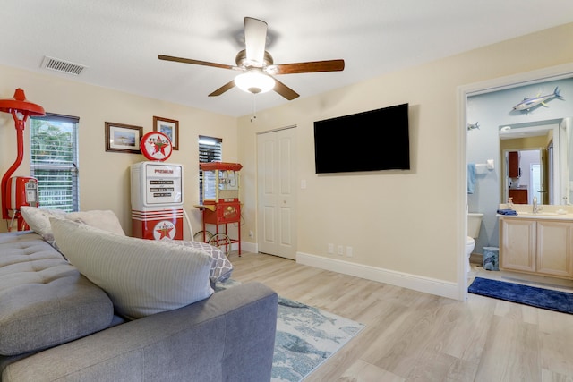 living room with sink, light wood-type flooring, and ceiling fan