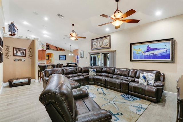 living room with lofted ceiling, ceiling fan, and light wood-type flooring