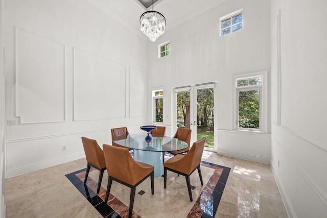 dining space featuring french doors, an inviting chandelier, crown molding, and a high ceiling