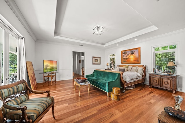 bedroom featuring crown molding, a raised ceiling, multiple windows, and light hardwood / wood-style flooring