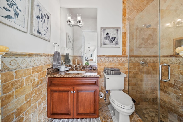 bathroom with vanity, a shower with door, an inviting chandelier, toilet, and tile walls