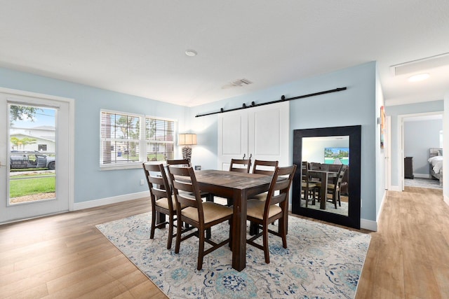 dining area with a barn door and light hardwood / wood-style flooring