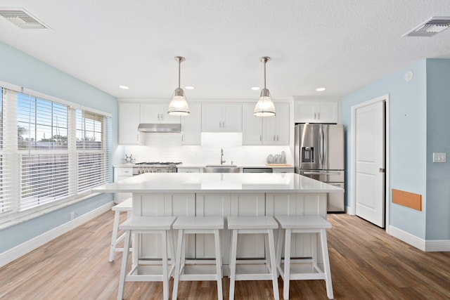 kitchen with sink, a kitchen island, stainless steel fridge with ice dispenser, pendant lighting, and white cabinets