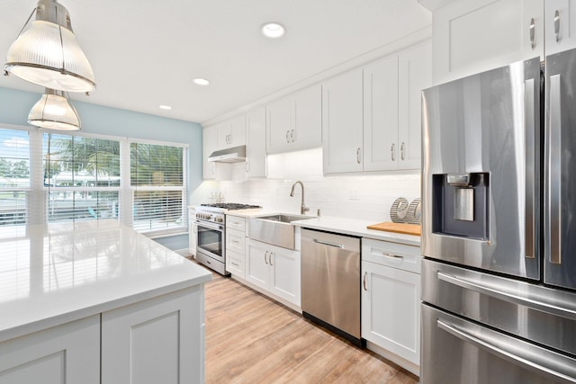 kitchen featuring pendant lighting, sink, appliances with stainless steel finishes, tasteful backsplash, and white cabinetry