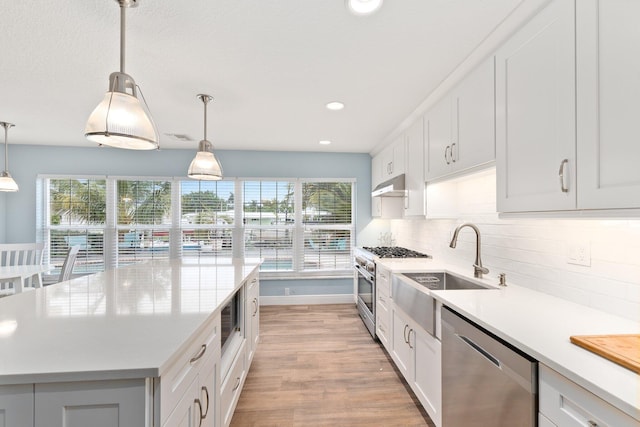 kitchen with decorative light fixtures, a center island, stainless steel appliances, and white cabinetry