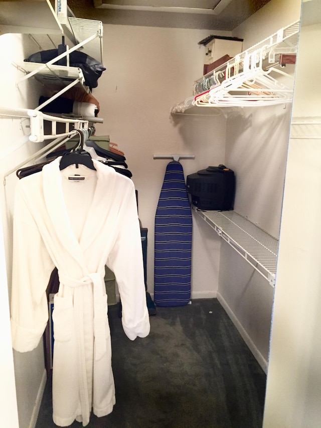 walk in closet featuring dark colored carpet