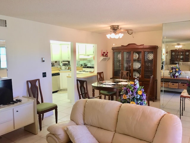 living room featuring ceiling fan, a textured ceiling, and light tile patterned floors