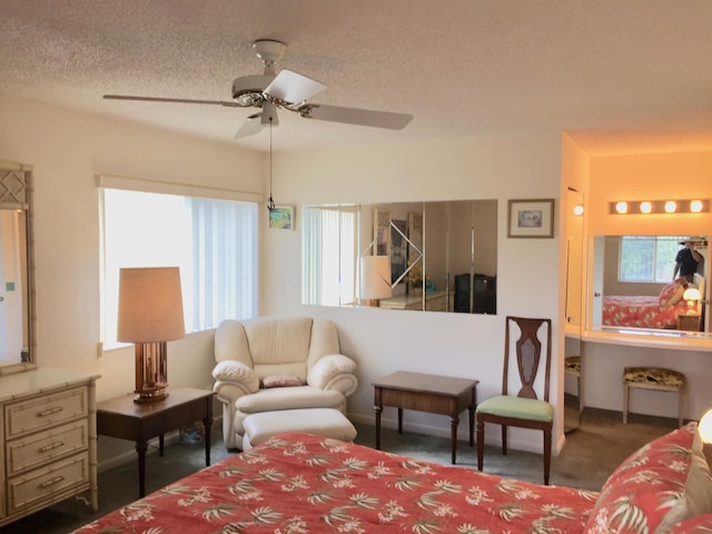 bedroom with ceiling fan, dark carpet, and a textured ceiling