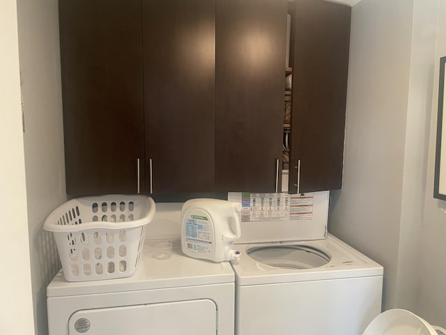 laundry room with separate washer and dryer and cabinets