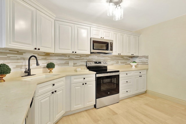 kitchen featuring sink, stainless steel appliances, backsplash, and white cabinets