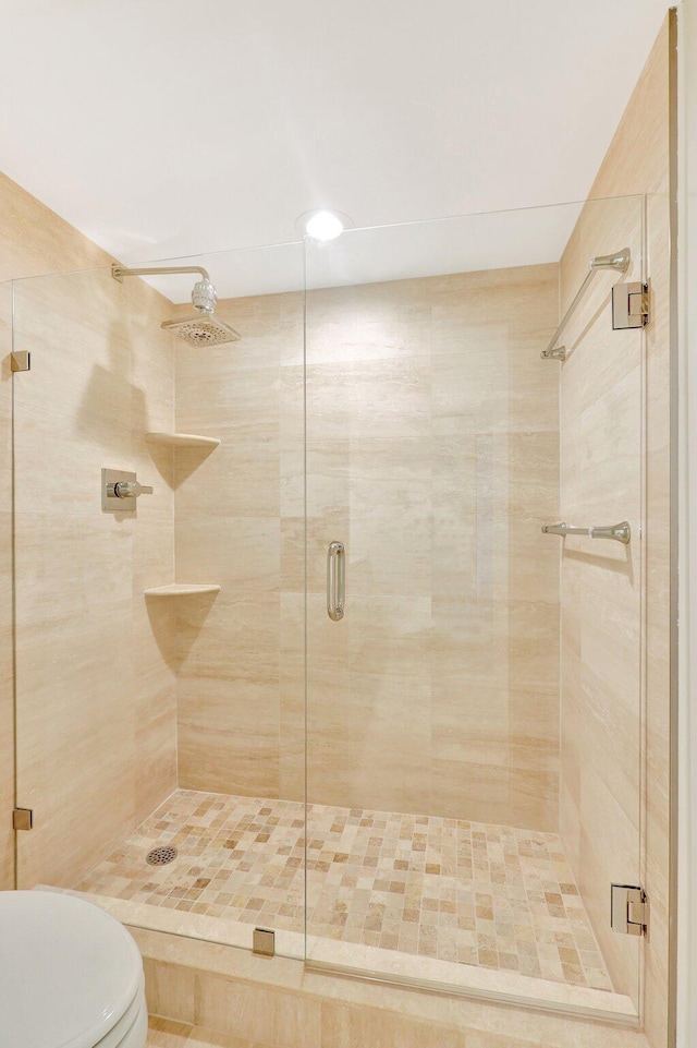 bathroom featuring toilet and a shower with door