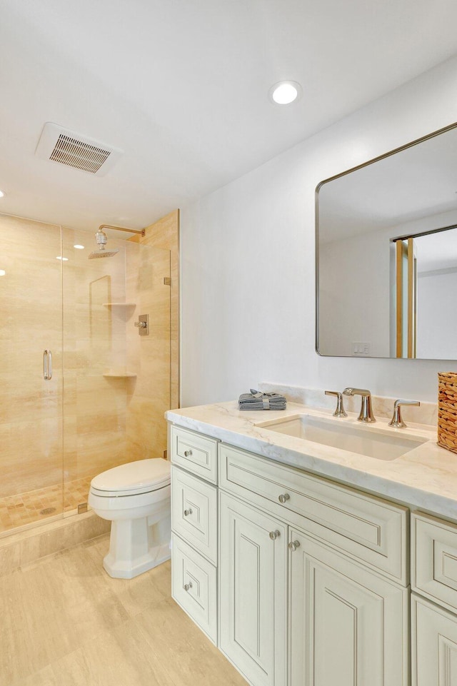 bathroom featuring a shower with door, vanity, and toilet