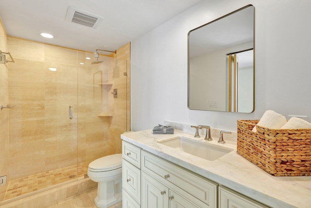 bathroom featuring a shower with door, toilet, and vanity