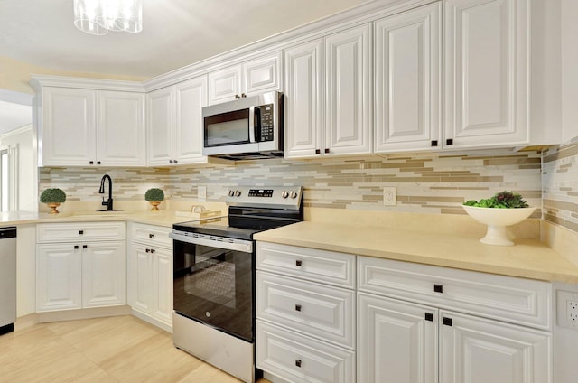 kitchen featuring sink, decorative backsplash, appliances with stainless steel finishes, and white cabinets