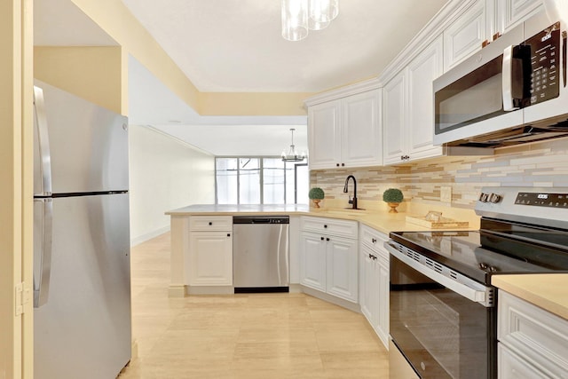 kitchen featuring tasteful backsplash, an inviting chandelier, white cabinets, hanging light fixtures, and appliances with stainless steel finishes