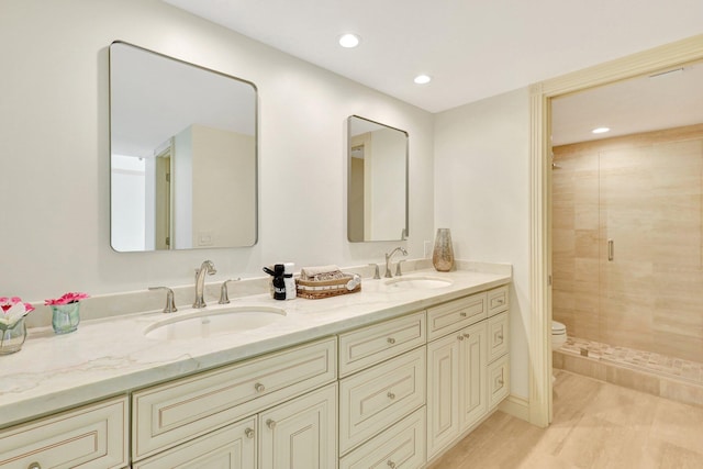 bathroom featuring dual vanity, toilet, a shower with shower door, and hardwood / wood-style floors