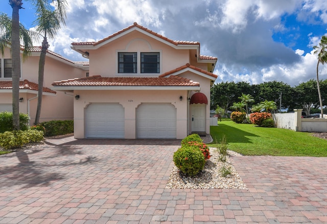 mediterranean / spanish house featuring a front lawn, decorative driveway, a garage, and stucco siding