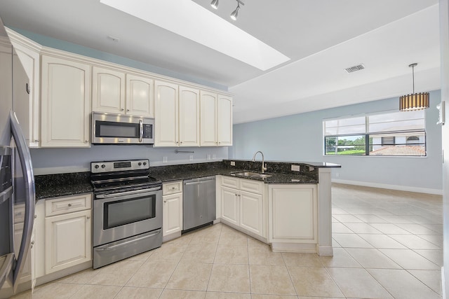 kitchen with stainless steel appliances, dark stone counters, kitchen peninsula, and sink