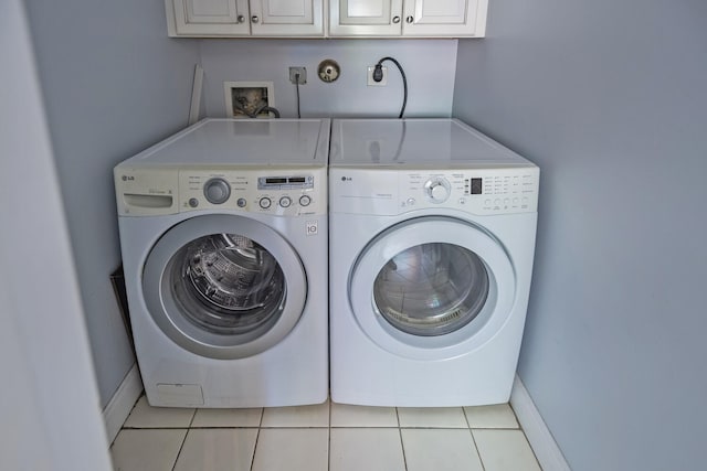 laundry area featuring cabinets, washer and clothes dryer, and light tile patterned flooring