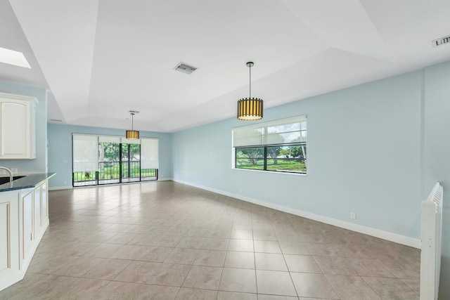 interior space with a tray ceiling, plenty of natural light, and light tile patterned floors