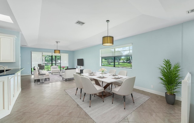 tiled dining space featuring a skylight and a raised ceiling